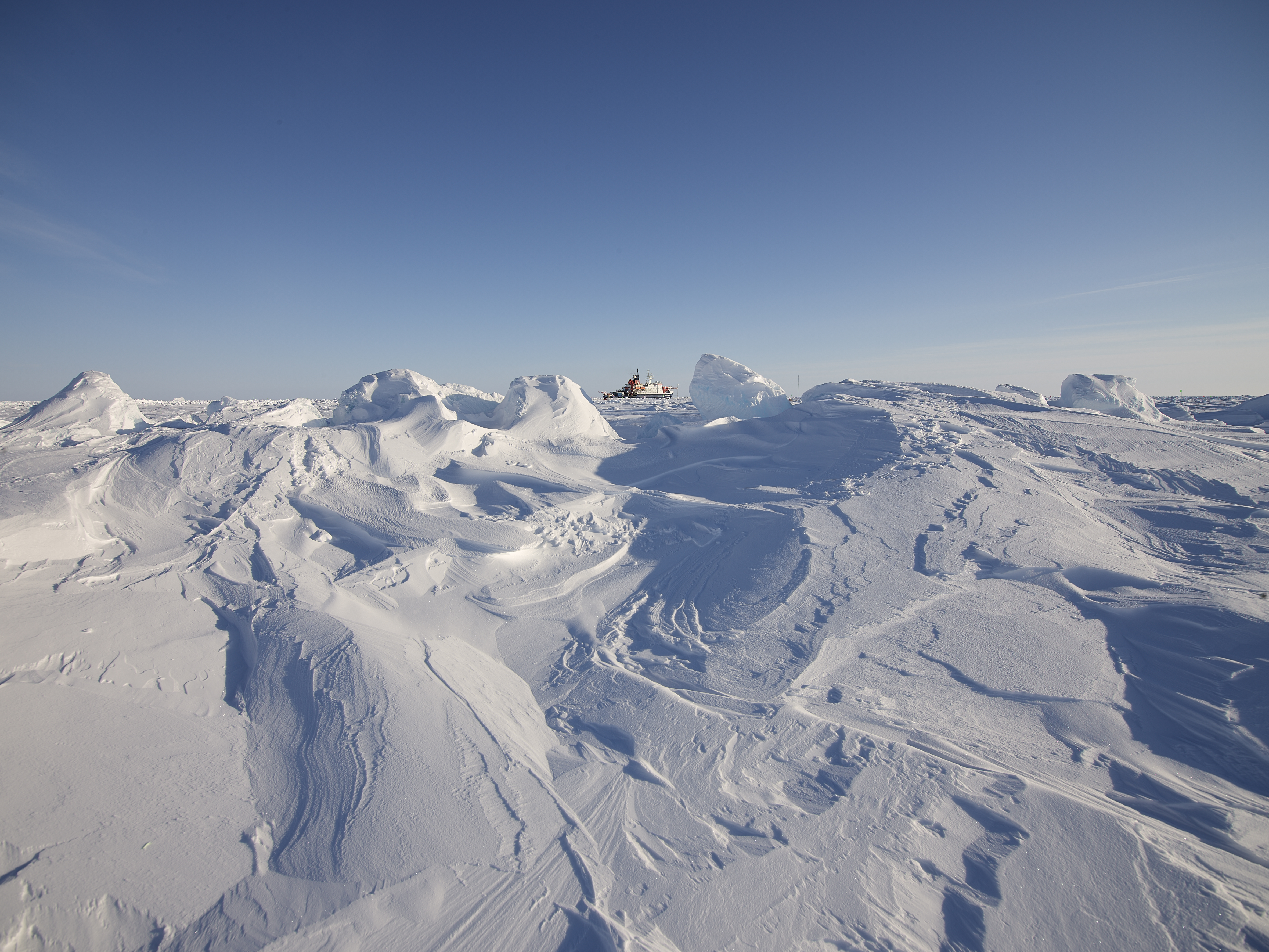 MOSAiC. Photo Michael Gutsche. Arctic ice dominating the picture in the front with small Polarstern on the horizon MOSAiC. Photo Michael Gutsche. Arctic ice dominating the picture in the front with small Polarstern on the horizon