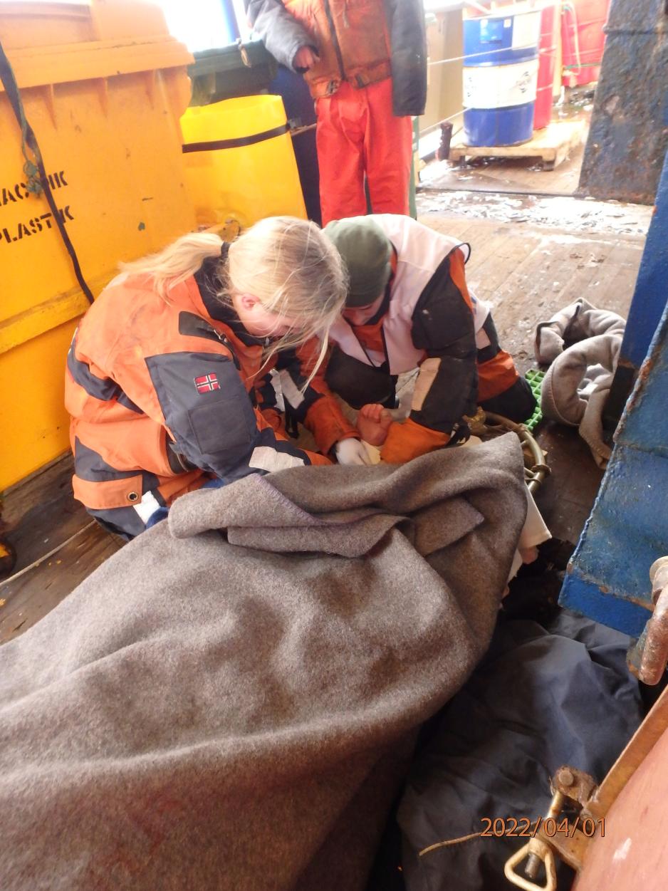 Sanitetslaget fra kystvaktskipet KV Jarl i aksjon med å hjelpe den skadede fiskeren på en russisk tråler forrige fredag. (Foto: Kystvakten). 