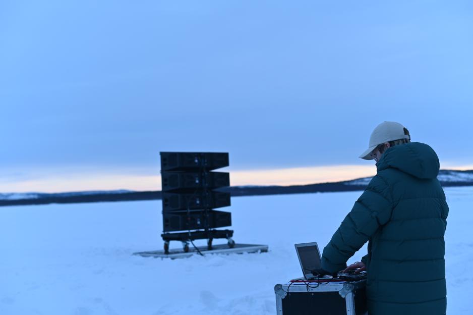 I slutten av februar 2022 ble Barents Spektakel avrundet med symboltung stillhet fra russisk side av Pasvikelva. Som et verk om lytting og brobygging over store avstander, skulle den norske kunstneren Tine Surel Lange (på bildet) og hennes russisk-ukrainske kollega Pavlo Grazhdanskij spille av tåkesignaler til hverandre over grenseelva ved hjelp av kraftige høyttalere. Lyden av tåkeluren fra norsk side fikk ingen gjenklang da russiske myndigheter brått satte en stopper for framføringen. På årets Spektakel deler de to kunstnerne sine refleksjoner rundt tillit. (Foto: Ingrid Fadnes)