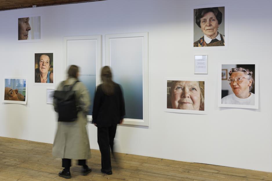 Publikummere på vernissasje betrakter verkene til Jaakko Heikkilä i kapittelet ‘Grenselandet’: River og Jesus Stands on the Other Side. Heikkiläs fotografier forteller om Torneälven og folk som bor på begge sider av den. Elven renner fra Nord-Sverige og danner i sørøst grense til Finland før den munner ut i Bottenviken. (Foto: Mats Engfors/Havremagasinet)