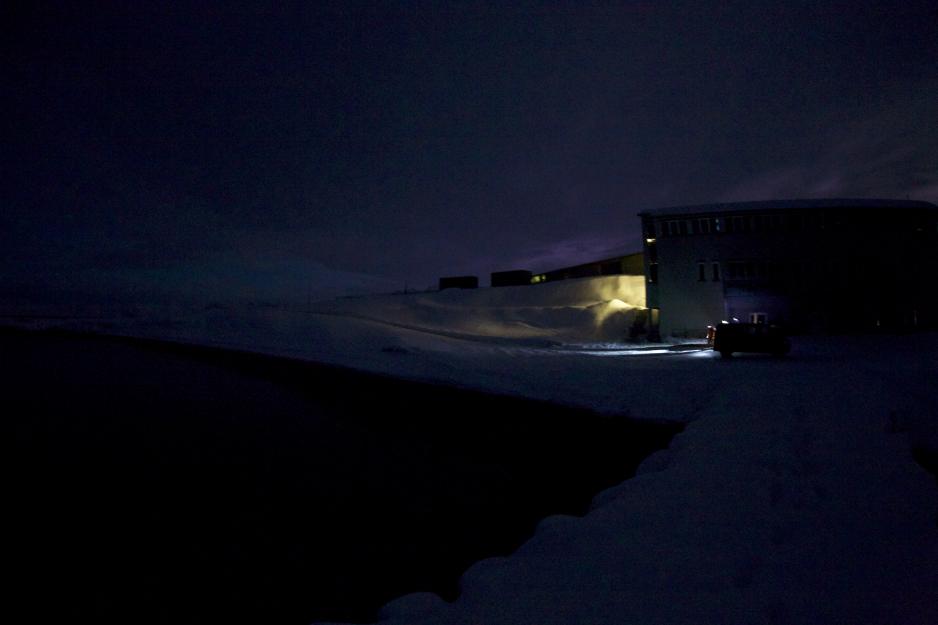 Marinlaboratoriet i Ny-Ålesund – som tatt ut fra en krigshistorie er alle vinduer tettet igjen med dobbelt lag sorte søppelsekker for at kunstig lys ikke skal skinne ut. Ikke for å hindre at noen potensiell fiende skal ha problemer med å se laboratoriet, men for å unngå ”lysforurensing” av havmiljøet utenfor der forskerene jobber intensivt for å avdekke mørkets hemmeligheter. Foto: Jørgen Berge, UNIS.