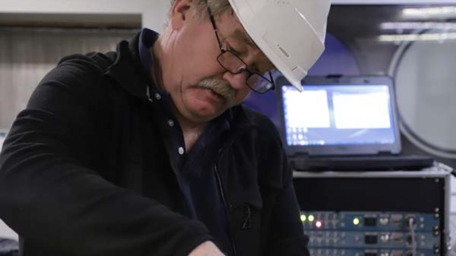 Franck Andersen fra Universitetet i Bergen (UiB) åpner opp en seismisk mottaker før han kobler den til en PC (bak ham på bildet) for dataoverføring. Franck Andersen