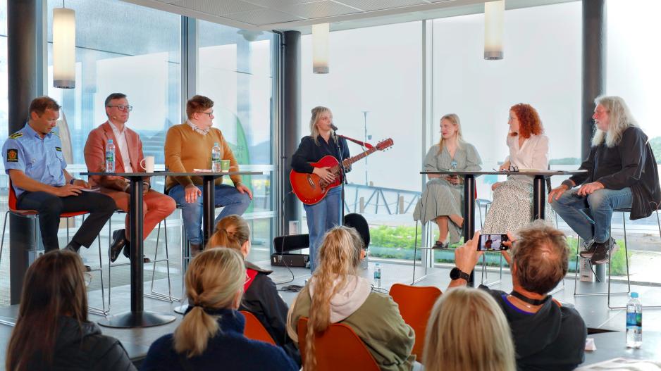 BILDEGALLERI: High Noon mandag om oppvekstvilkår i nord: Musikalsk innslag ved artist og låtskriver Thea Glenton Raknes. Panel (f.v.): Politiinspektør Yngve Myrvoll, FEFE-leder, Troms politidistrikt; Dag Rune Olsen, rektor, UiT; Martin Gamst Johnsen, fhv. leder, Barents regionale ungdomsråd; Luna Drecker, leder, Tromsø ungdomsråd; Rebekka Brox Liabø, skrivepedagog og dramatiker. (Alle foto: Astri Edvardsen) >