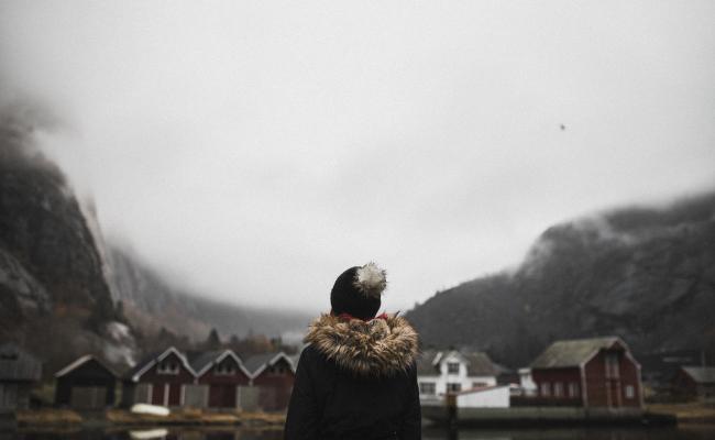 Kvinne med ryggen til i en bygd. AdobeStock.