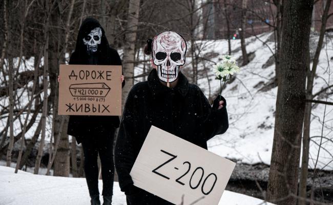 Medlemmer av De dødes parti (Партия мёртвых), en russisk kunstnerisk protestgruppe, demonstrerer mot krigen i Ukraina på en kirkegård i St. Petersburg. På plakaten til den «døde» til venstre står det «Дороже живых» – «Mer verdifulle enn de levende». Teksten «Z-200» til den andre «døde» henspiller på russiske styrkers krigssymbol «Z», og den militære koden «cargo 200» for transport av lik fra slagmarken. (Foto: De dødes parti).