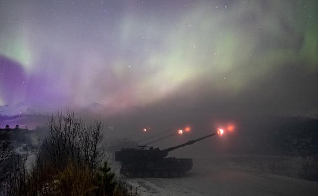 Arctic Bolt 2022: Den samlede Artilleribataljonen i Brigade Nord fyrer av langtrekkende ild og kruttrøyken formelig smelter sammen med nordlyset. (Foto: Ole-Sverre Haugli/Forsvaret)